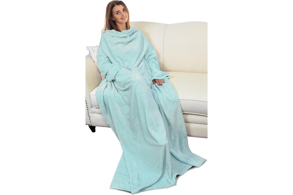 A woman sitting on a couch wrapped in a Snuggie blanket