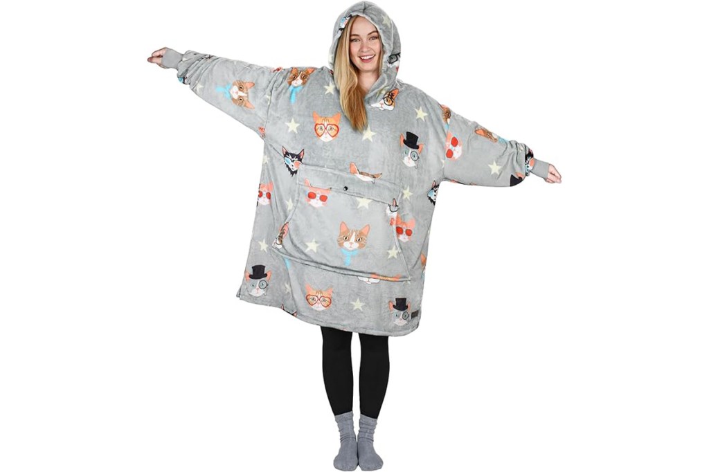 A woman wearing a grey blanket with cartoon cats and stars