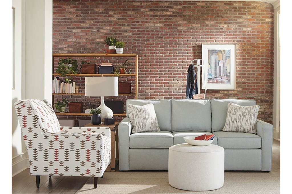 A living room featuring a couch against a brick wall