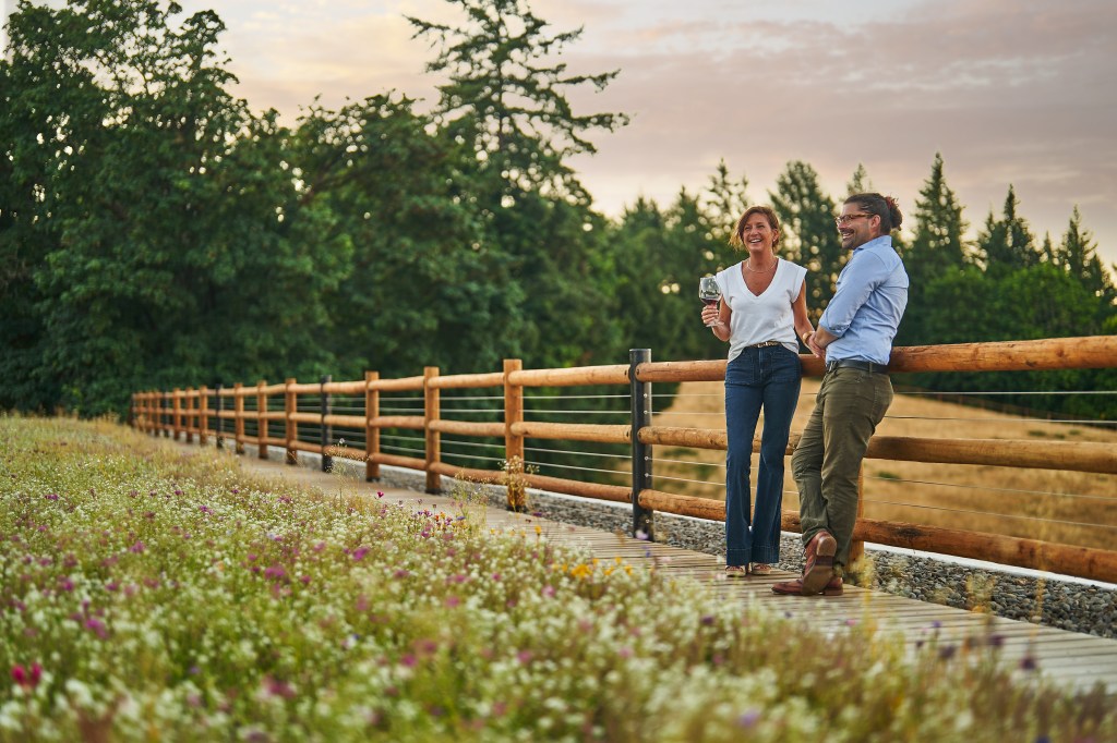 A man and woman standing on a wooden bridge at Inn the Ground farm.