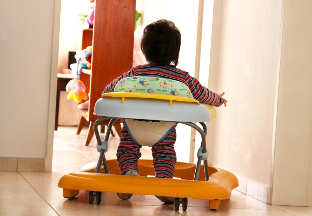 A baby learning to walk in a sit-in baby walker