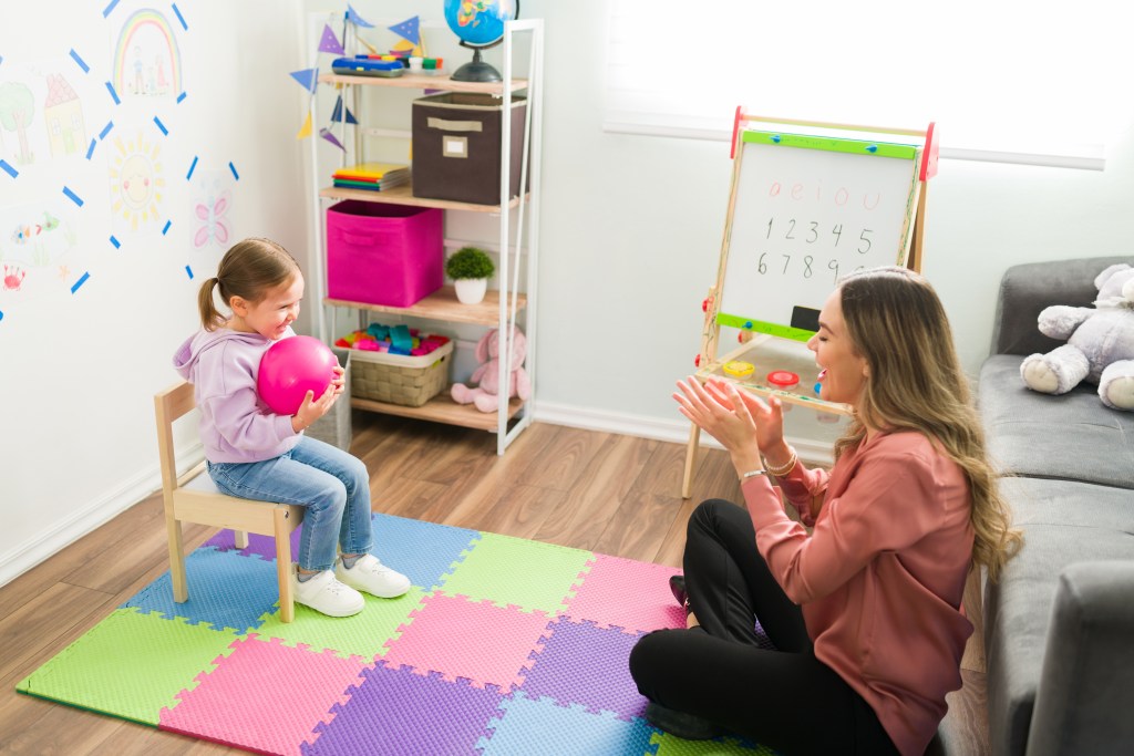 Beautiful girl smiling while holding a ball during a child therapy session.