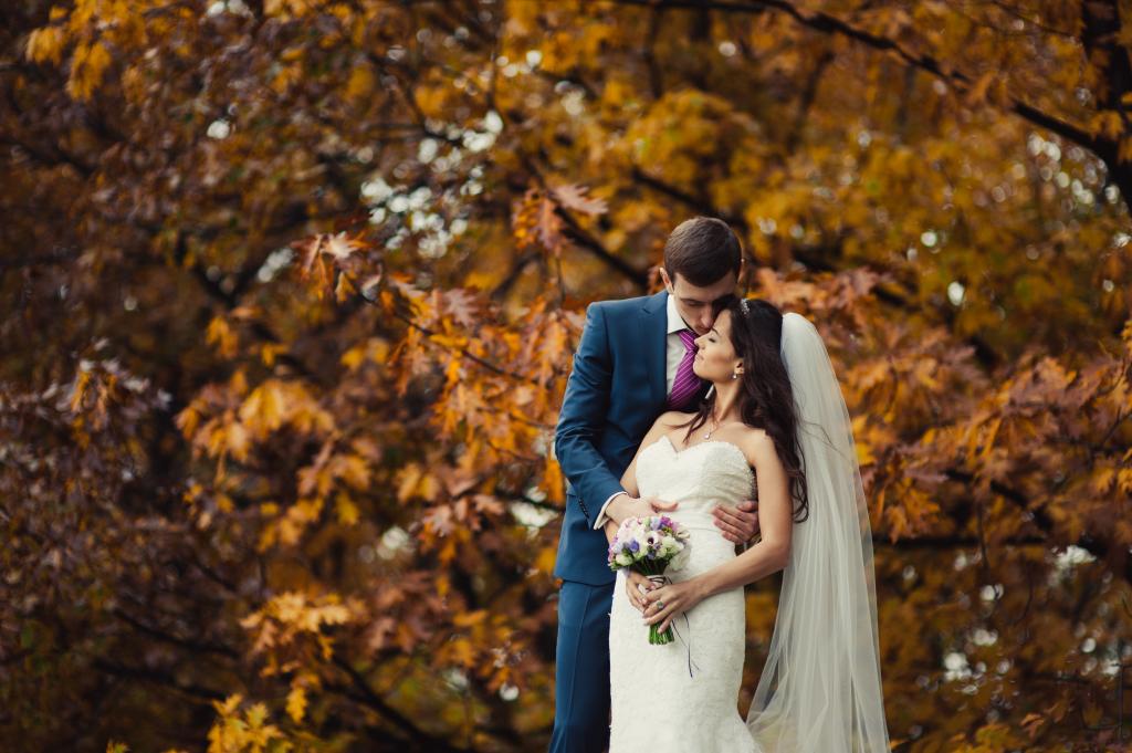 A beautiful wedding couple kissing during a walk in an autumn park