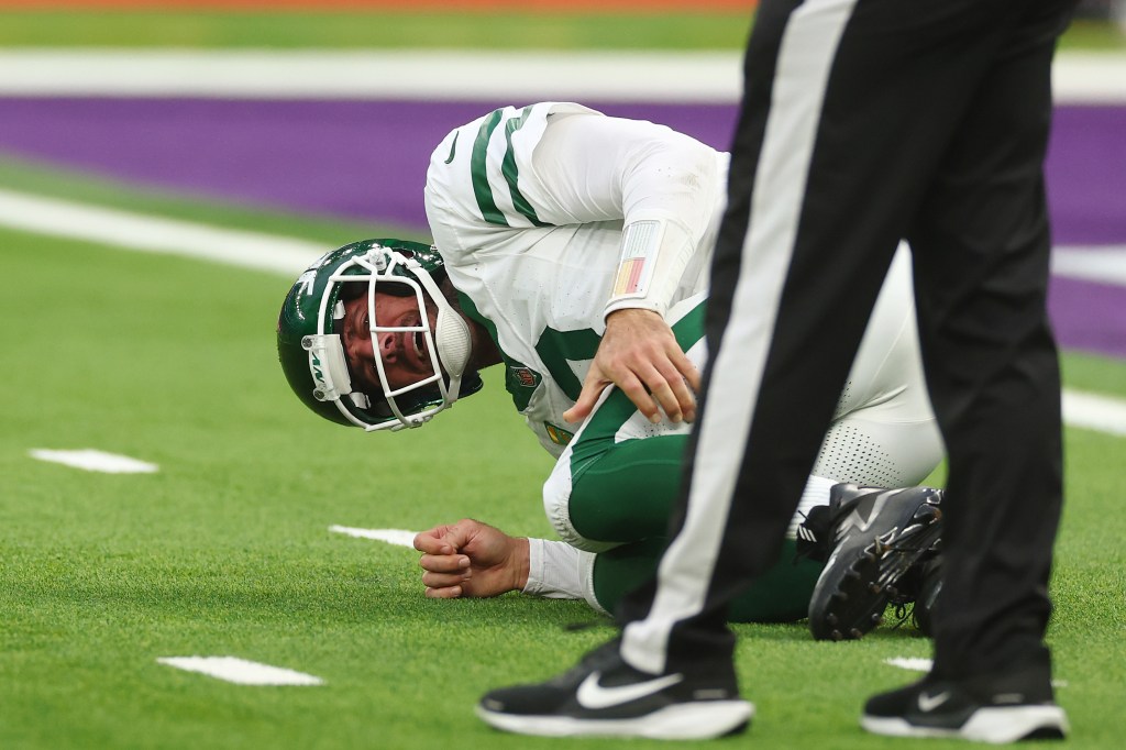 Jets quarterback Aaron Rodgers grabs his leg after getting hit by the Vikings in London on Oct. 6, 2024.