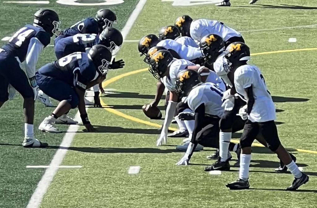 James Madison High School junior varsity football team practicing on the field, seen facing another team in navy uniforms