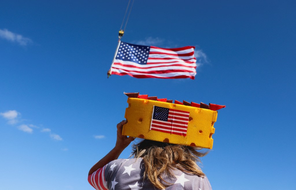 A supporter of Republican presidential nominee and former U.S. President Donald Trump looks at a U.S. flag as they attend his rally in Juneau, Wisconsin, U.S., October 6, 2024.