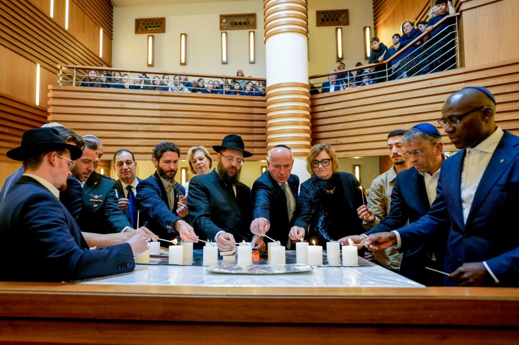 Survivor Alon Gat, Rabi Yehuda Teichtal, and Berlin mayor Kai Wegner holding a candle-lighting ceremony at the synagogue of the Chabad community in Berlin to mark the first anniversary of the Hamas attacks on Israel