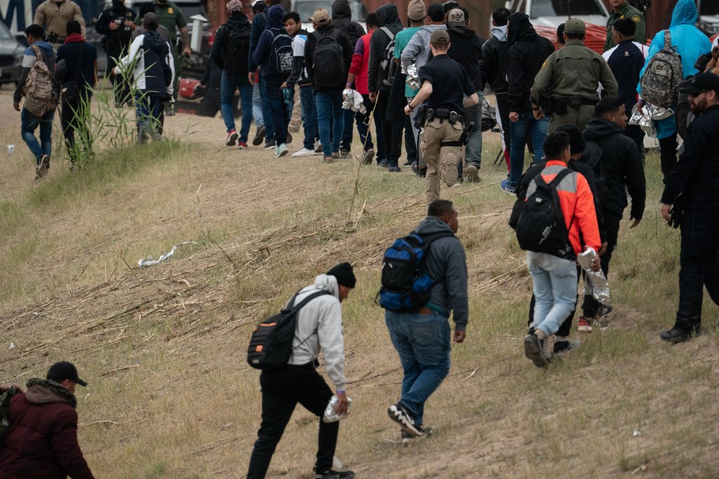 Dozens of migrants wait to be processed by border agents after crossing the Rio Grande river into Eagle Pass, Texas.