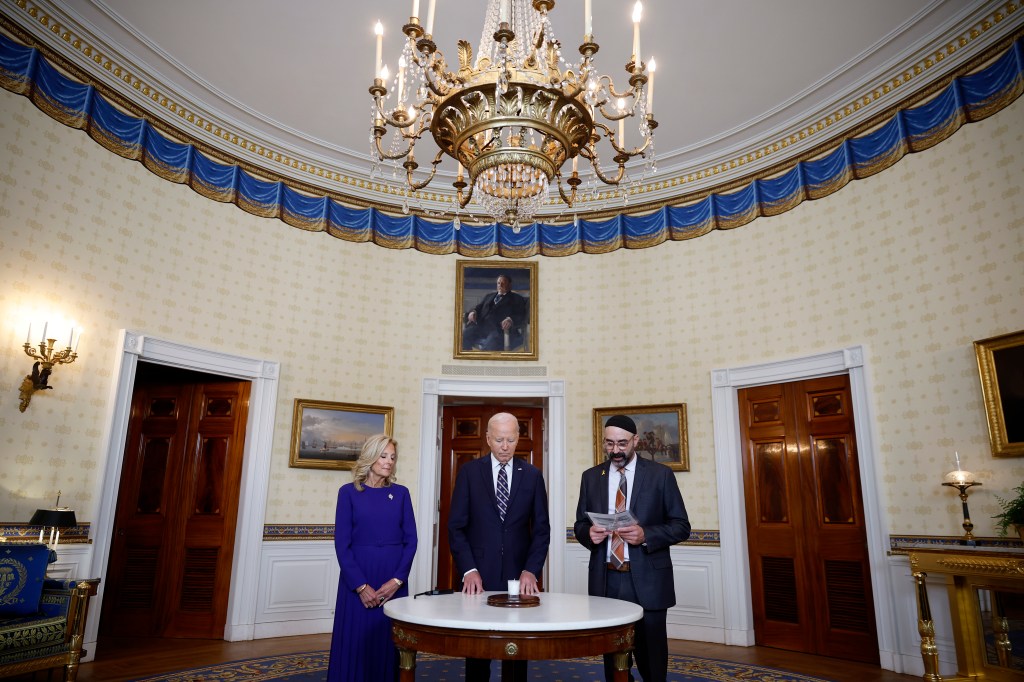 Joe Biden and First Lady Jill Biden standing with Rabbi Aaron Alexander at a remembrance ceremony in the Blue Room of the White House.