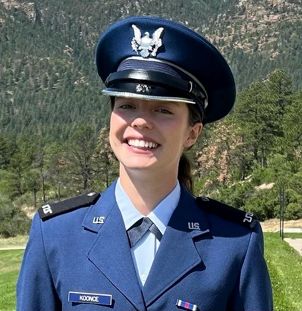 United States Air Force Academy Cadet 4th Class Avery Koonce smiles inher uniform with trees behind her.