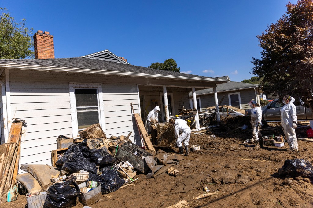 Volunteers in white overalls helping residents clean their mud-covered homes after Hurricane Helene in Swannanoa, North Carolina, October 7, 2024.