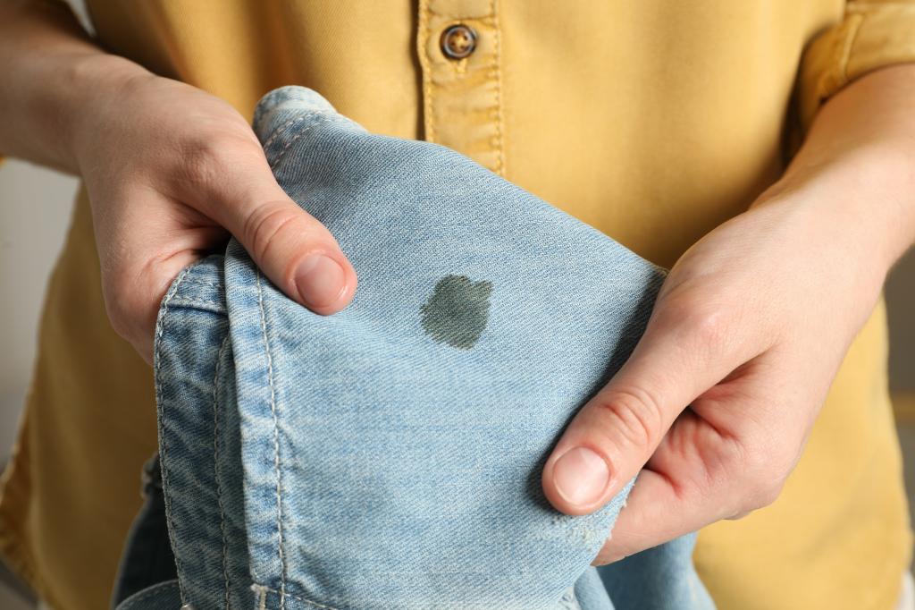 Woman holding a pair of stained jeans during laundry process, closeup