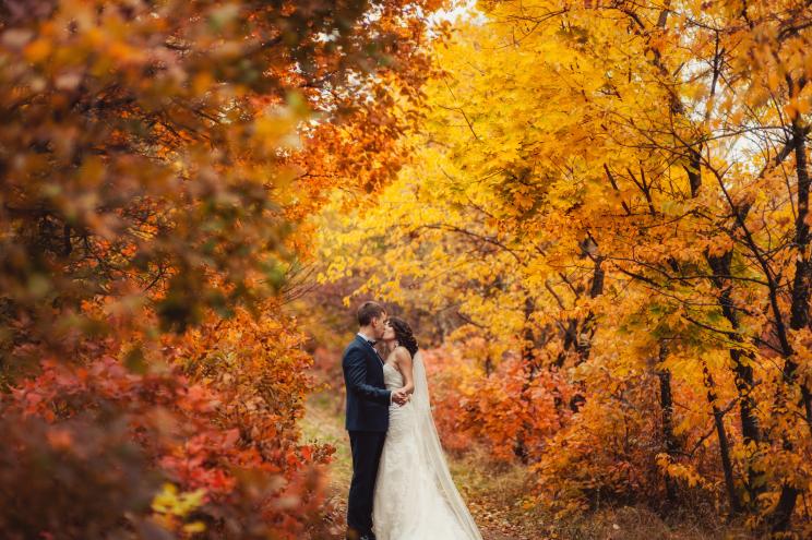 A wedding couple kissing during a walk in an autumn park