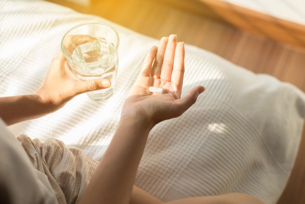 Woman holding a handful of pills or capsules and a glass of water