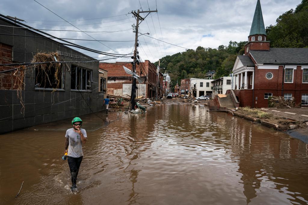 Workers and community members cleaning up debris on a flooded street in the aftermath of Hurricane Helene in Marshall, North Carolina.