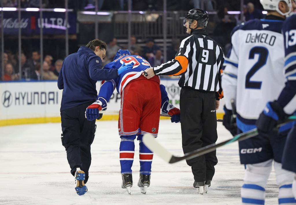 Mika Zibanejad #93 of the New York Rangers is checked on by a referee and a trainer during the second period.