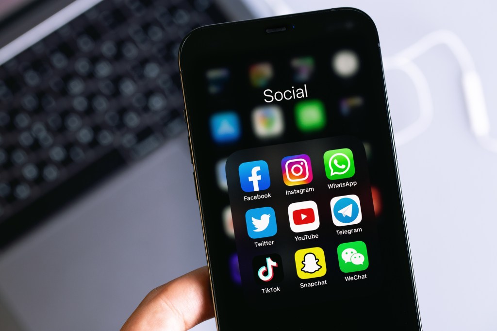 Hand holding an iPhone with social media apps like Facebook, Instagram, WhatsApp, Twitter, YouTube, Telegram, TikTok, Snapchat, and WeChat on screen, Moscow, Russia - January 16, 2021