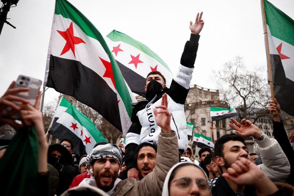 Supporters and members of the Syrian community wave the Syrian opposition flag in Trafalgar Square, central London, on December 8, 2024, to celebrate the fall of the al-Assad regime. 