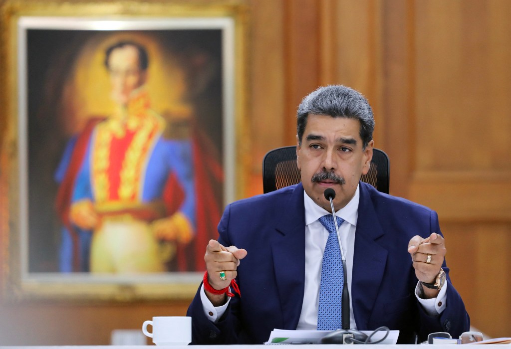 Venezuelan President, Nicolas Maduro, sitting at a desk during a press conference in Caracas, surrounded by microphones on January 8, 2025