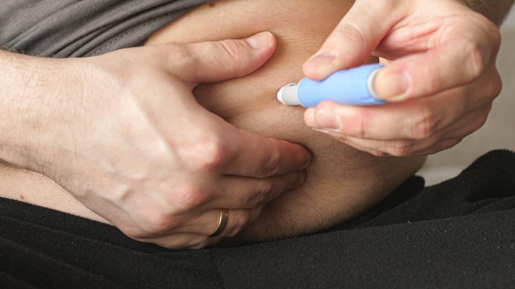 Man jabbing himself with Ozempic needle in stomach