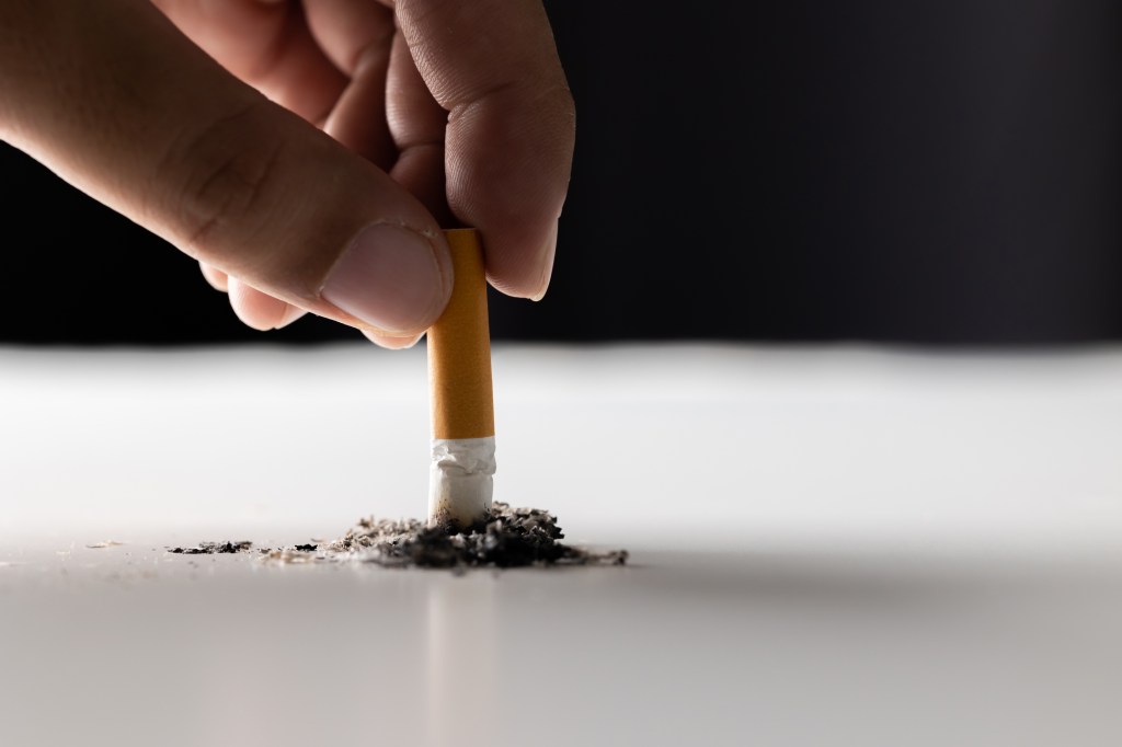 Close up hand putting out a cigarette. man extinguished his cigarette by crushing the floor. He smoked a lot of cigarettes