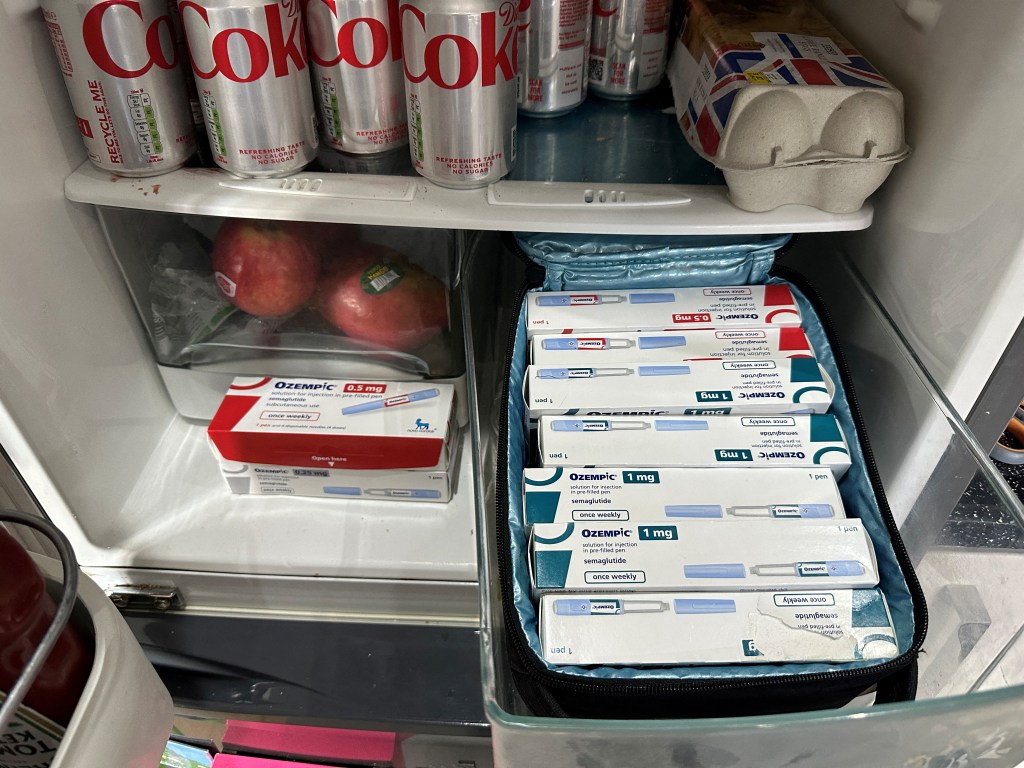 Boxes of Ozempic in a fridge with Diet Coke, eggs, and apples.