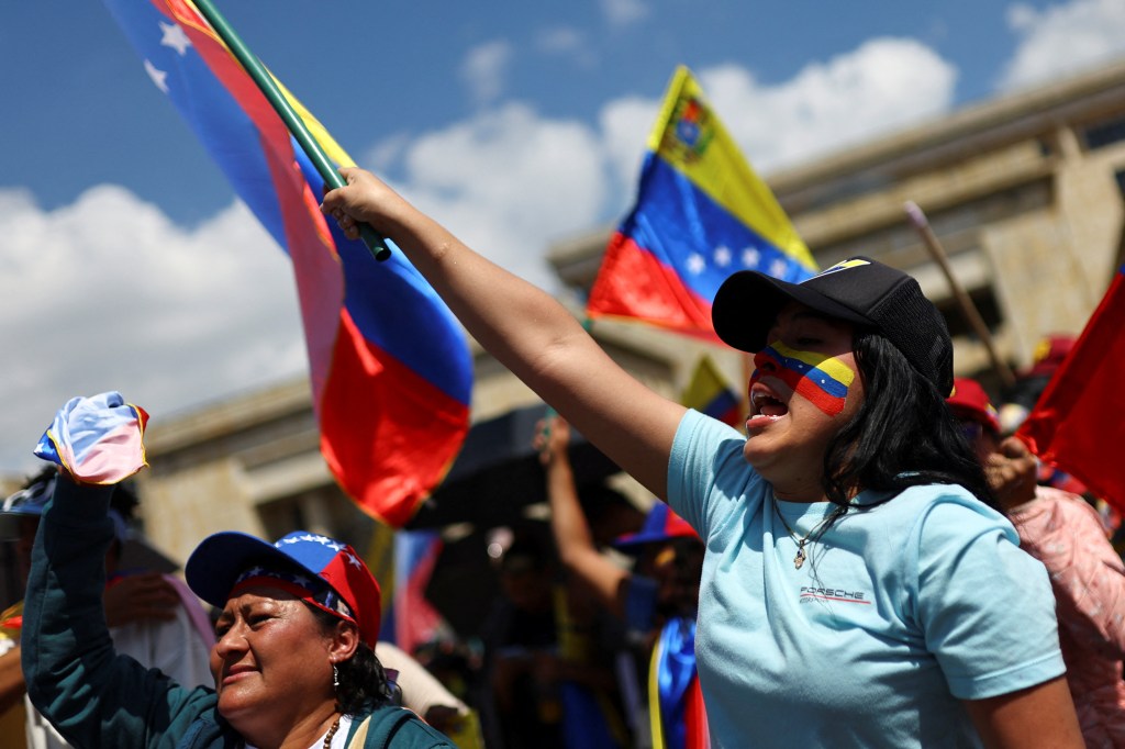 Supporters of Venezuela's opposition, including Smriti Mehra, holding flags in protest against President Nicolas Maduro's third term inauguration in Bogota, Colombia