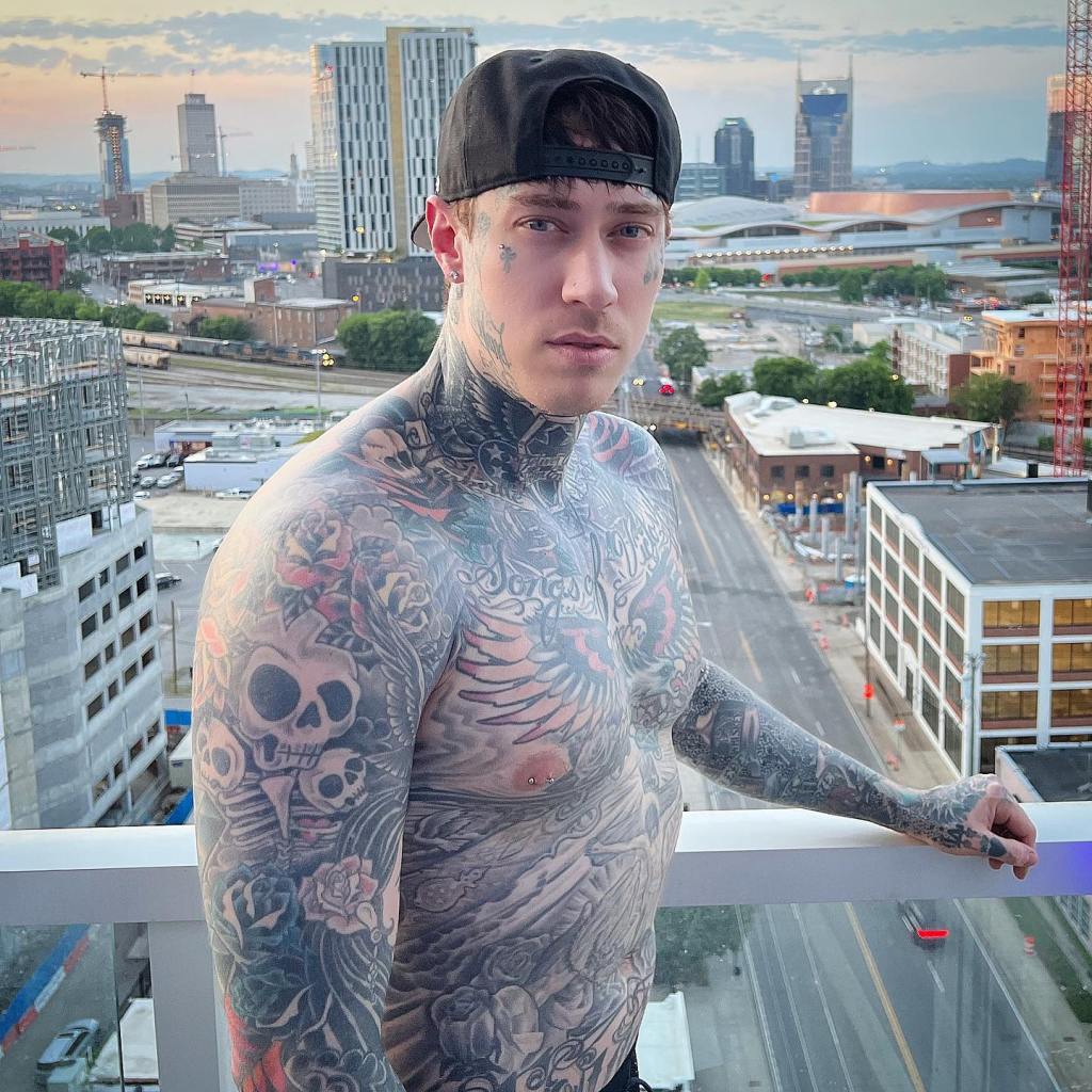 Trace Cyrus posted a message on Instagram asking his dad to get help. Here, Trace Cyrus on a balcony, shirtless, covered in tattoos. 
