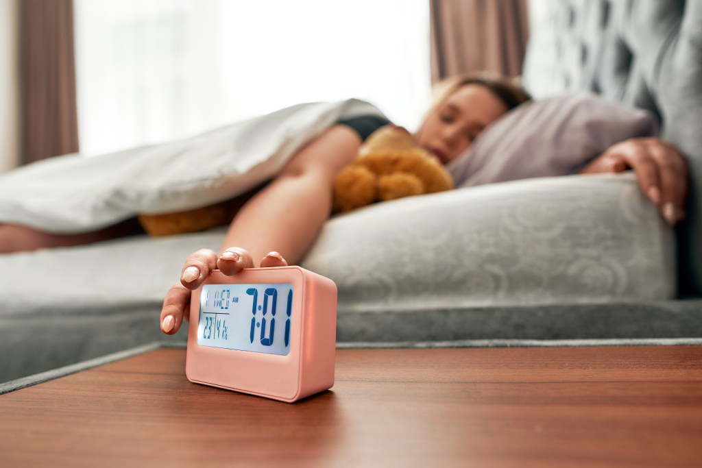 Young woman pressing snooze.
