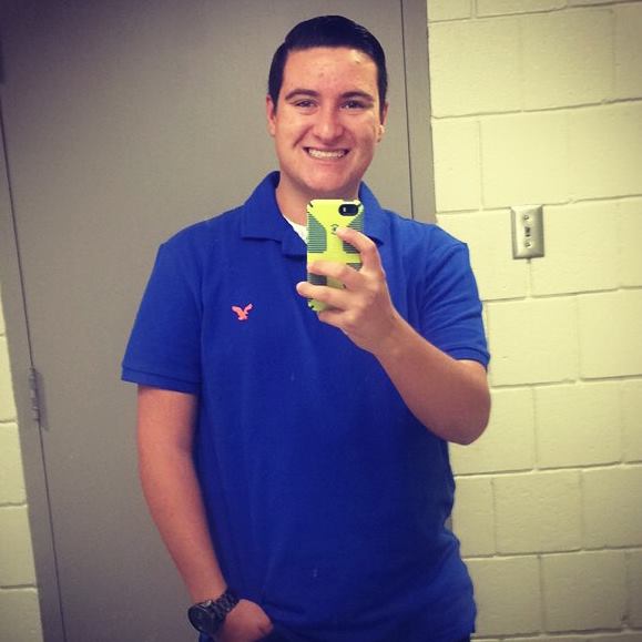 Carter McIntosh in a polo shirt looking like he is outside of his dorm room.