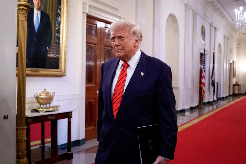 President Donald Trump walking down a hallway with a red carpet.