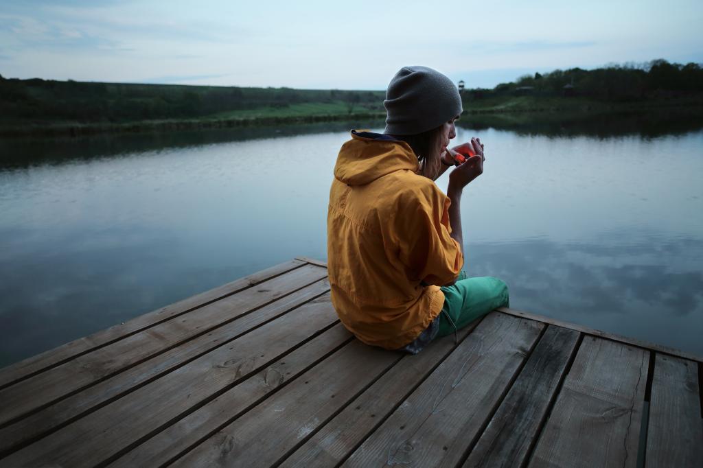 Young male athlete smoking marijuana near a river at sunset