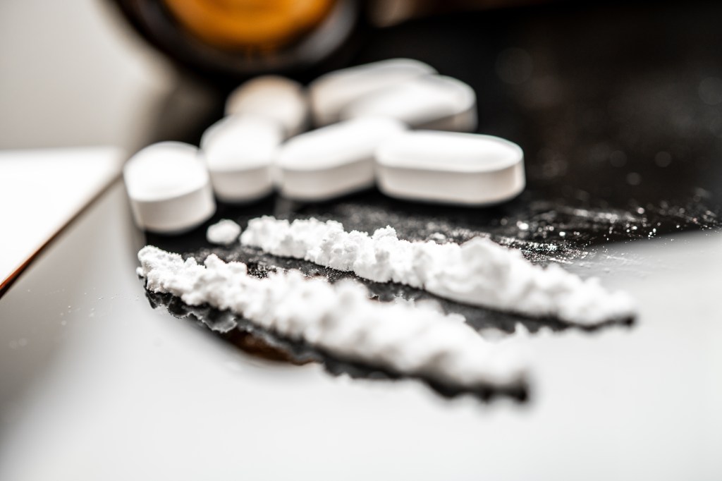 Fentanyl powder lines are positioned beside prescription opioid tablets.