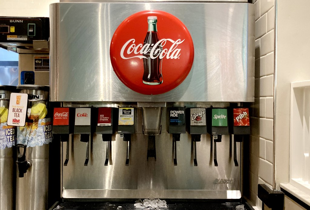 The new study linked each additional small glass of cola to 20% to 26% lower odds of healthy aging. Coca-Cola soda fountain with various beverage dispensers.
