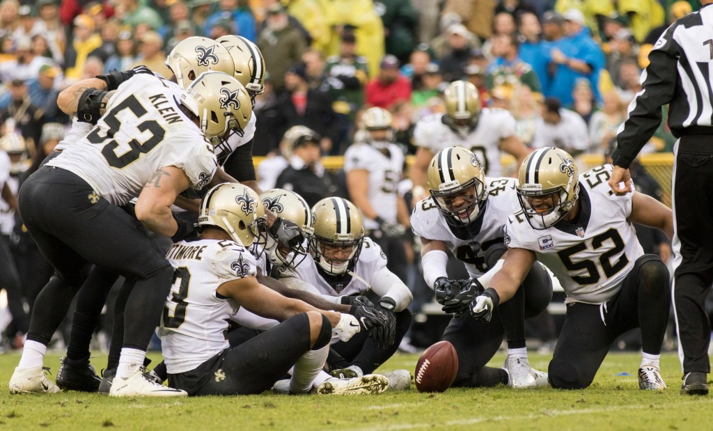 New Orleans Saints players celebrating around a spinning ball after interception during their 2017 game against Green Bay Packers