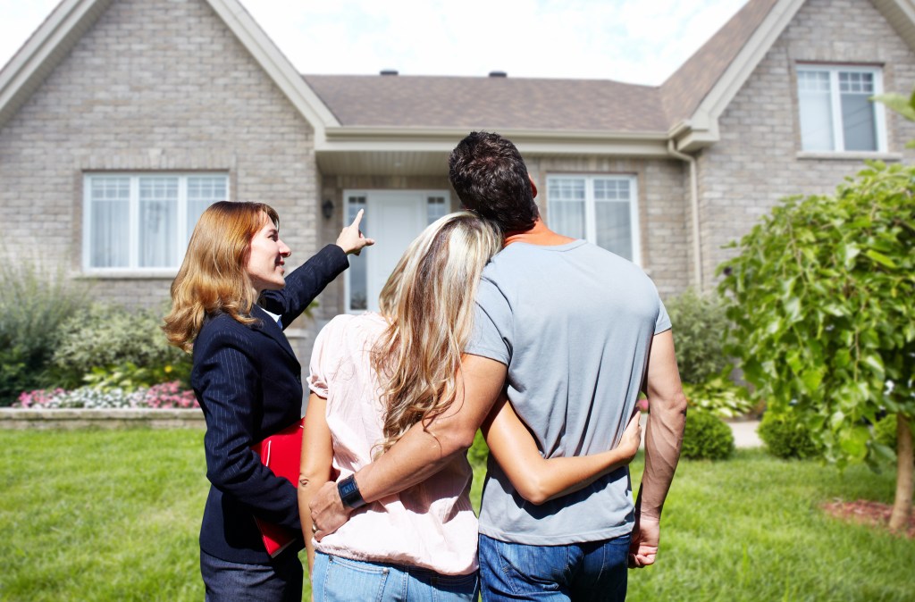 Real Estate agent woman near new house. Home for sale concept.