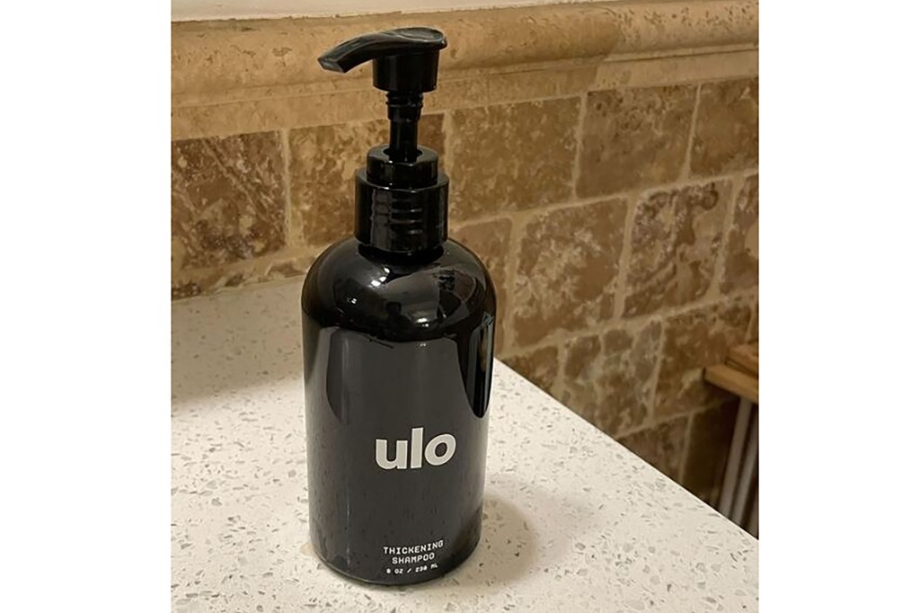 A black bottle of Ulo shampoo with a dispenser on a counter