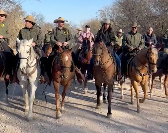 Kristi Noem on horseback with about a dozen border agents.