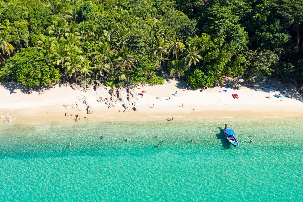 Banana Beach on the Thai island of Phuket came in second place globally. Here, view from above of a beautiful tropical beach with white sand, turquoise clear water, long-tail boat and people sunbathing, Banana beach, Phuket, Thailand.