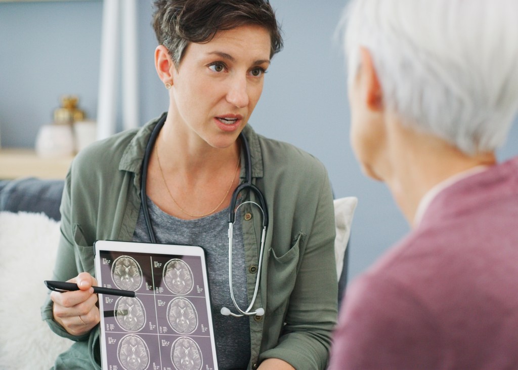 A doctor shows an older patient scans of his brain.
