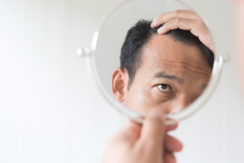 A man examining his hair, concerned about hair loss