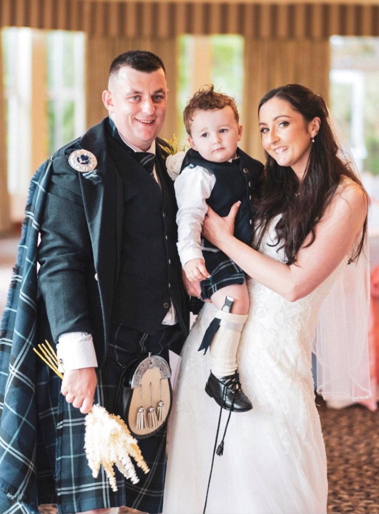Danielle Thomson and Mark Brodie holding their son Aaron on their wedding day at Crutherland House Hotel