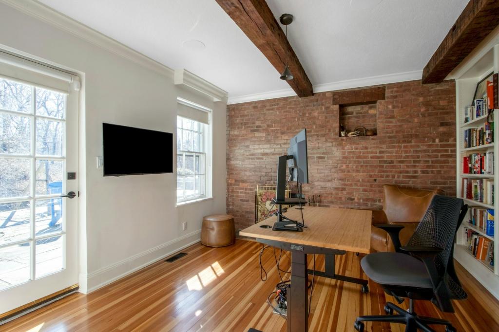 A home office features exposed brick and beamed ceiings