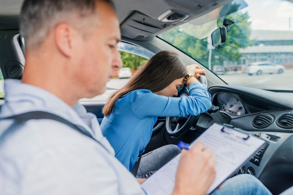 Disappointed woman with her head in her hand in a car, after failing her driving test with instructor Billy Kennedy