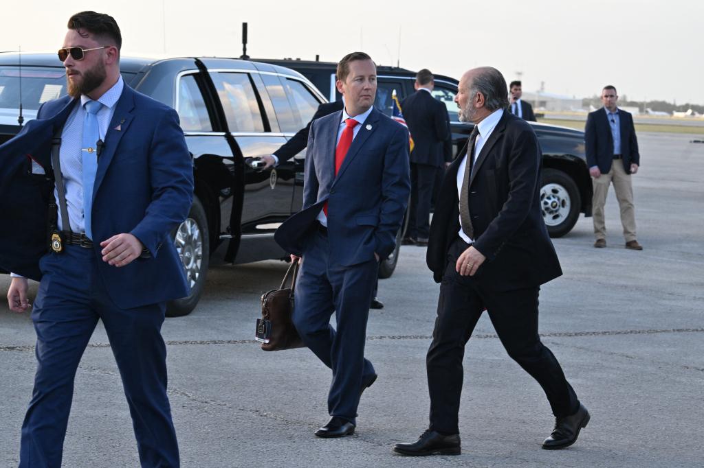 Sergio Gor and Howard Lutnick walking and chatting on the tarmac of Palm Beach International Airport after Donald Trump's arrival