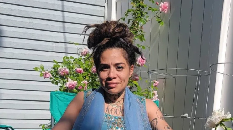 A photo of Adriana Alvarez sitting outside in a garden with pink roses in the background