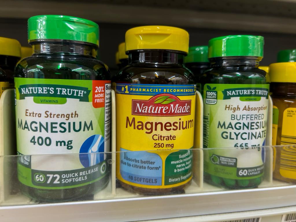 Magnesium supplement bottles for sale on a grocery store shelf.