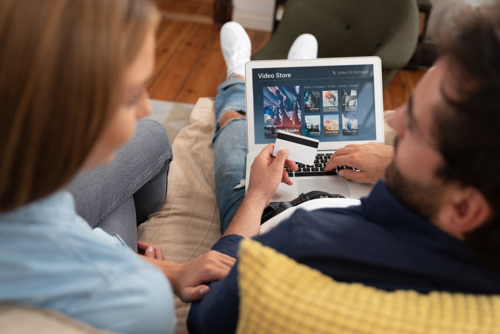 Couple purchasing a Video On Demand television subscription and watching a movie on their laptop