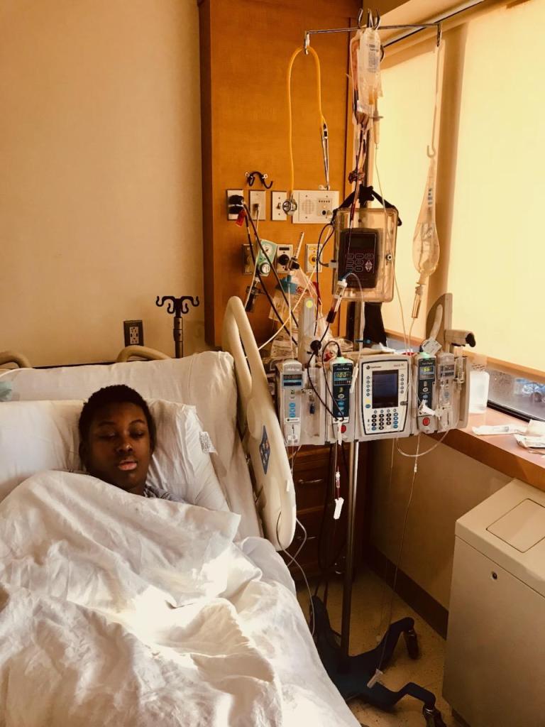 Sebastien Beauzile expressing mixed emotions in a hospital bed due to a year-long sickle cell treatments announcement in early 2024