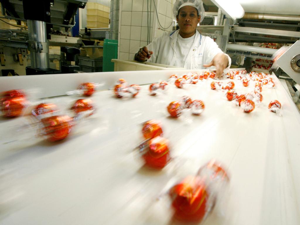 Employee controls Lindor praline truffles moving down conveyer belt.